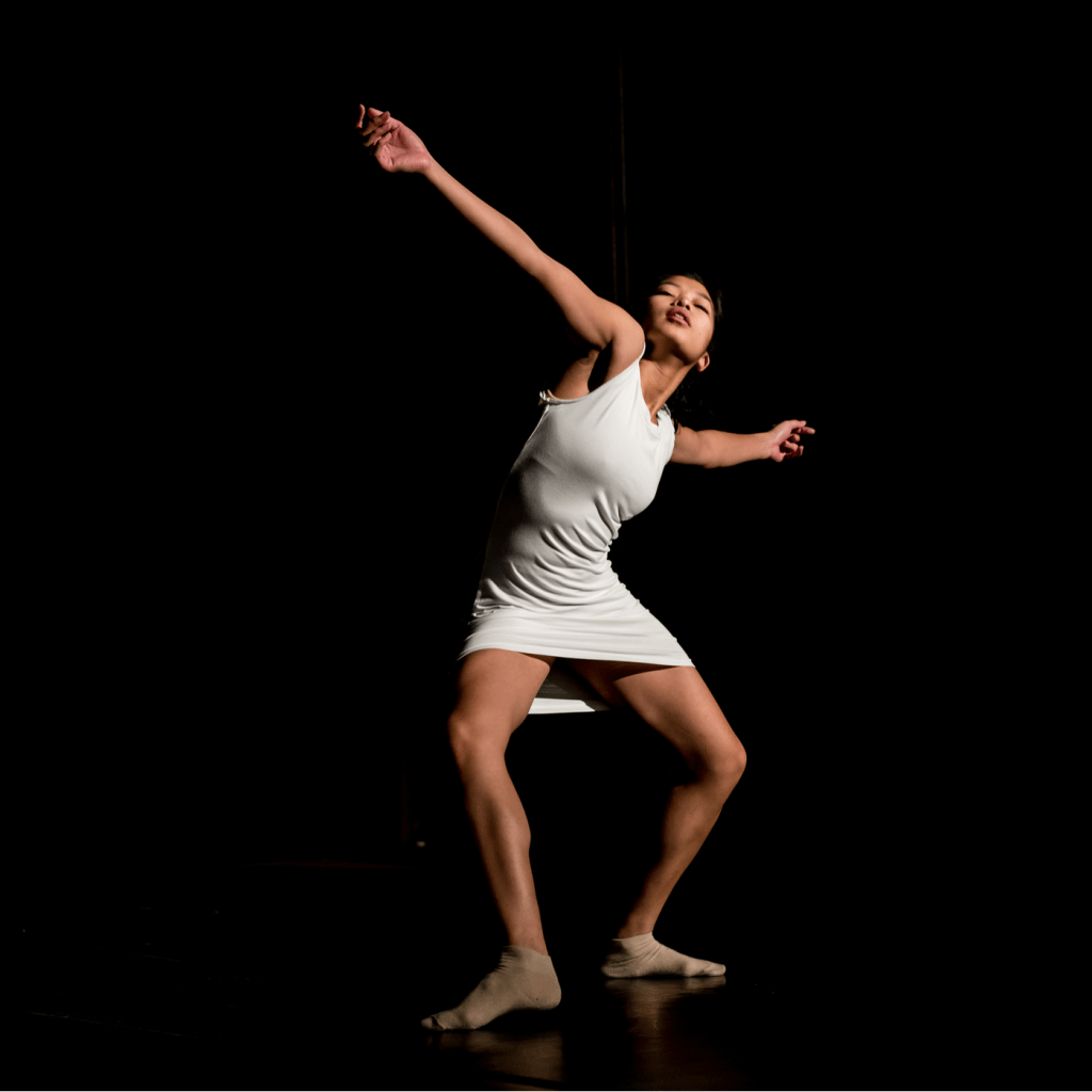 Ha Vo dancing on stage at Dominican University of California, wearing a white dress