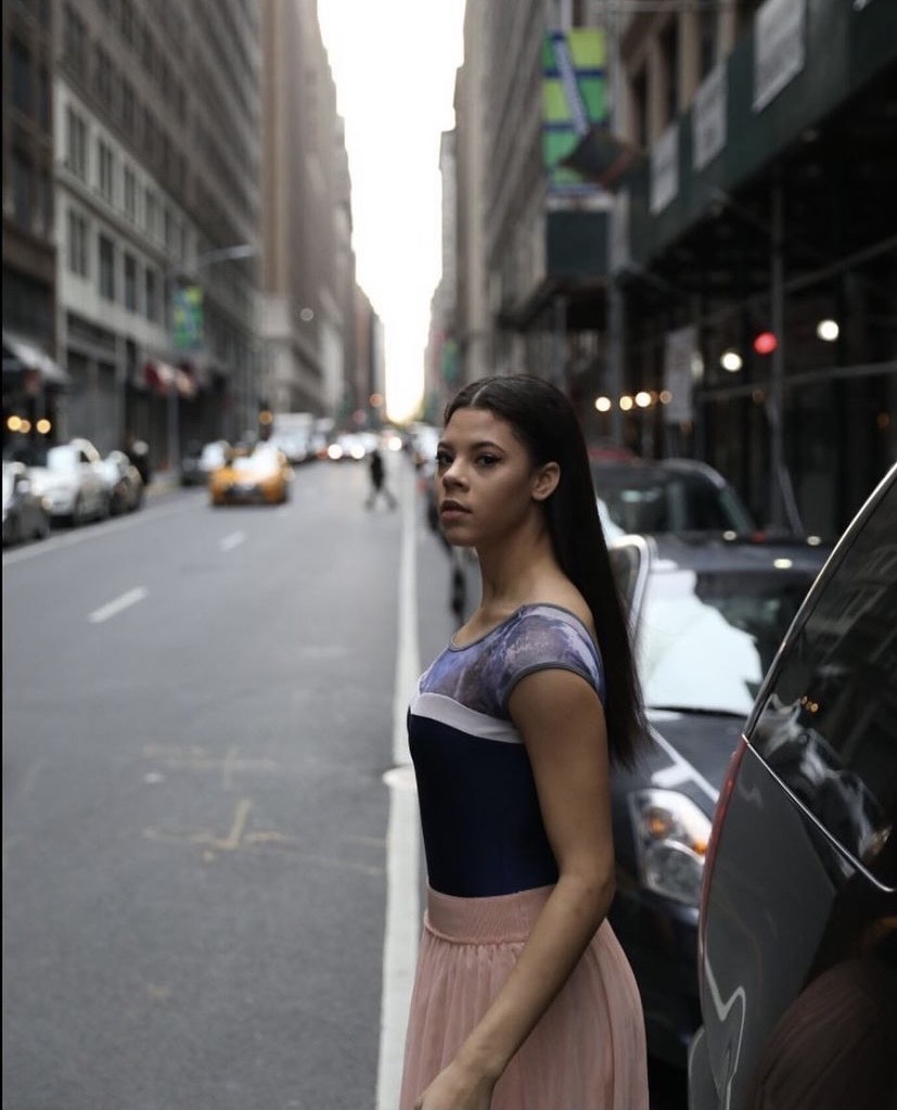 BFA Senior Devin Jones standing next to parked cars in the city street, looking into the camera