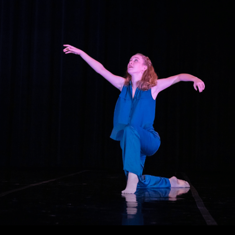 Hannah Woolfenden dancing on stage at Dominican University of California, wearing a blue outfit