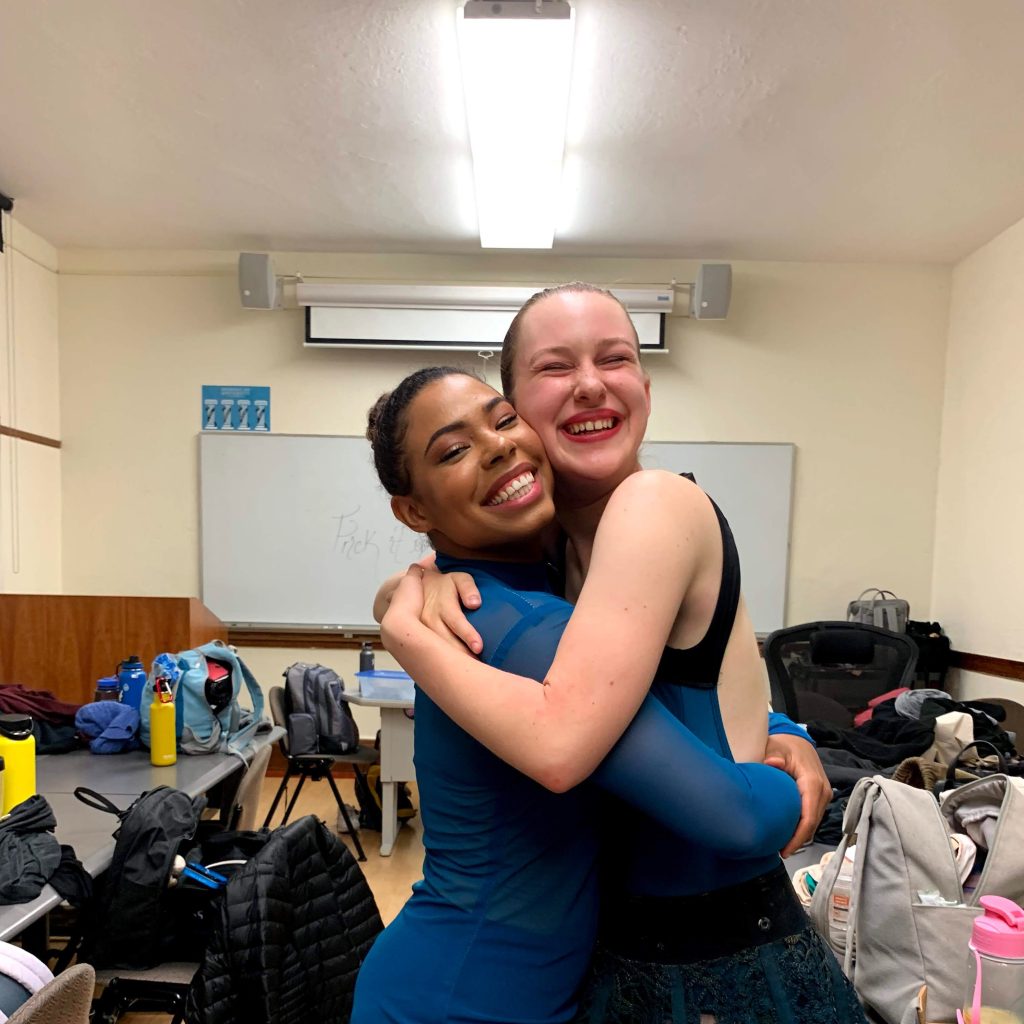 Angel Warden-Palmer and Hannah Woolfenden hugging backstage at one of their dance performances at Dominican University of California