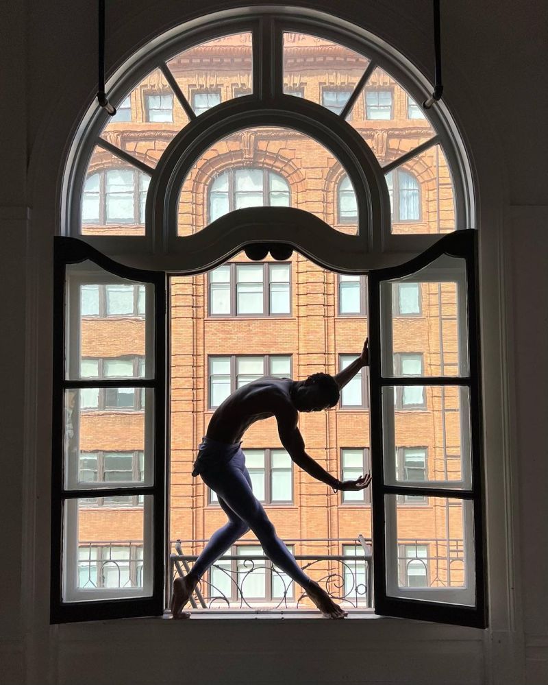 Josh Francique dancing in a window frame at LINES Dance Center