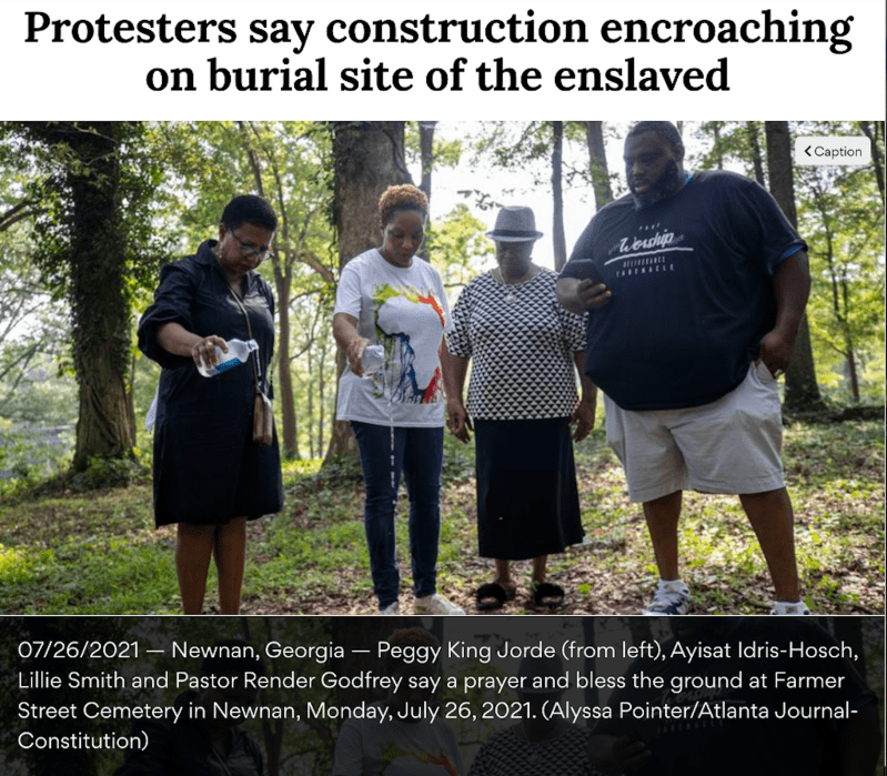 An article titled "Protesters say construction encroaching on burial site of the enslaved" features a photograph of Peggy King Jorde (from left), Ayisat Idris-Hosch, Lillie Smith, and Pastor Render Godfrey saying a prayer and blessing the ground at Farmer Street Cemetery in Newnan, Georgia. The caption underneath the photograph reads: "07/26/2021 — Newnan, Georgia — Peggy King Jorde (from left), Ayisat Idris-Hosch, Lillie Smith and Pastor Render Godfrey say a prayer and bless the ground at Farmer Street Cemetery in Newnan, Monday, July 26, 2021. (Alyssa Pointer/Atlanta Journal-Constitution)"
