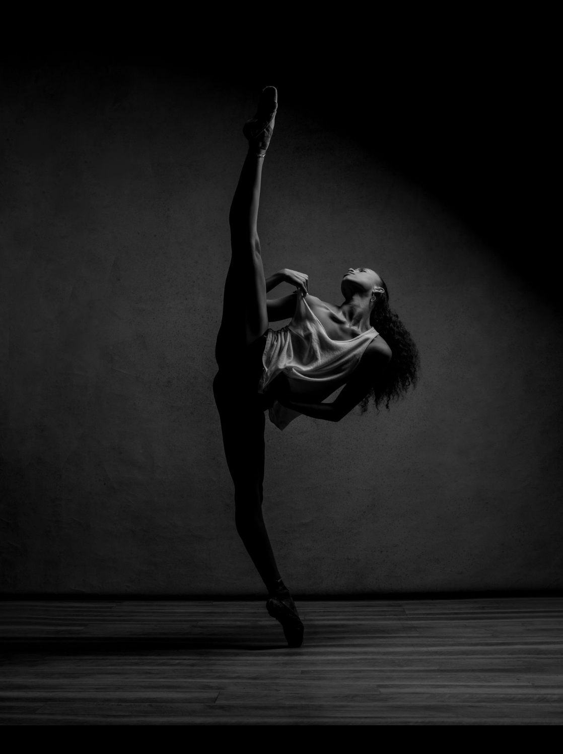 Amanda Smith dancing en pointe with leg extended to the side in a 180 degree tilt; the photograph is in black and white